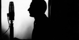 A silhouette of someone speaking into a large radio mic