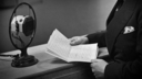 A close up picture of a black and white picture of a man by an old fashioned mic