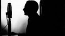 A silhouette of someone speaking into a large radio mic