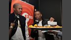Scorcher's not sure about the jerk chicken and patties that Vis offers him.