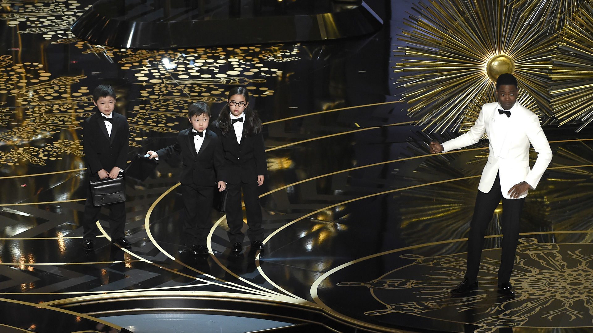 Chris Rock and children, mid-routine, on the 2016 Academy Awards telecast.