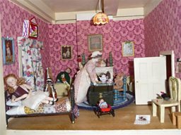 A doll's house room with a sampler on the wall
