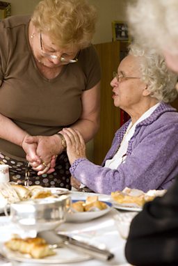 Two women chatting over a table of cakes