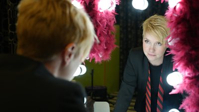 Person looking into a mirror in a dressing room.