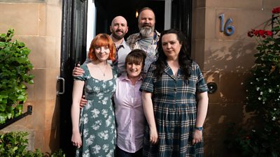 Five adults stand in the doorway of a house