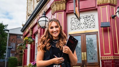 Ģ������Ƶ Studios colleague standing outside the Queen Victoria Pub holding a clipboard