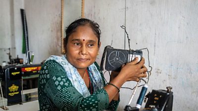 Basanti Chaudhary listens to her radio at home in Nepal. A sewing machine is in the foreground.