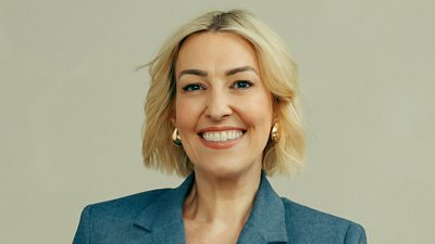 A head and shoulders shot of Kelly Cares, smiling to camera in a blue suit jacket
