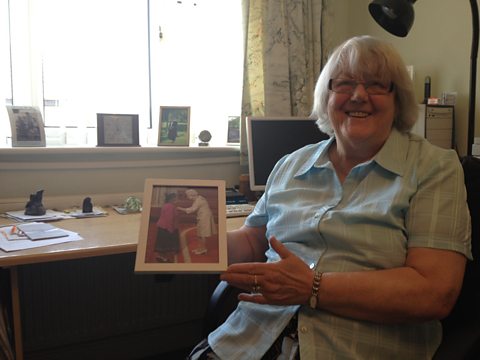 Jean Walker MBE, holding a photo of herself and the Queen