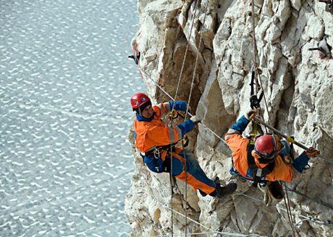 Bruce working at a zinc mine in Greenland, dangling 800 metres above sea level