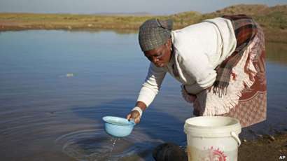 Woman collects water in Qunu