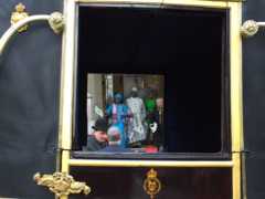 Picture taken through the window frame of a royal carriage shows Liberian ambassador on steps of the Langham