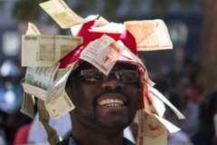 A man with old Zimbabwean dollars on a hat