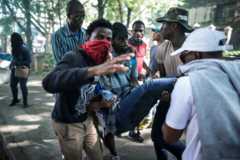 A wounded student is evacuated by fellow students during protest over higher tuition fees in Johannesburg on September 21, 2016.