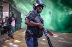 A South African police officer looks on during clashes with students from the University of the Witwatersrand during a protest agaisnt university fee increases on September 21, 2016 in Johannesburg, South Africa