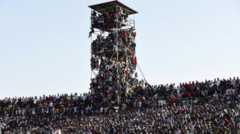 Fans fill the stands and are also crammed onto a tall viewing platform made out of scaffolding