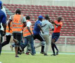 Fans charge at the referee as security staff rush to keep up