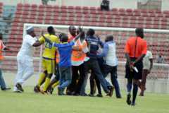 An angry group of fans and security officials encircle the ref on the pitch