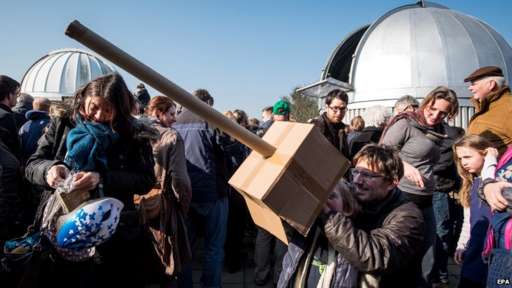 Hobby astronomer Hans-Ulrich and his son Tillmann gaze at the partial solar eclipse using a self-made pinhole camera made of cardboard in front the observatory in Hanover, Germany,