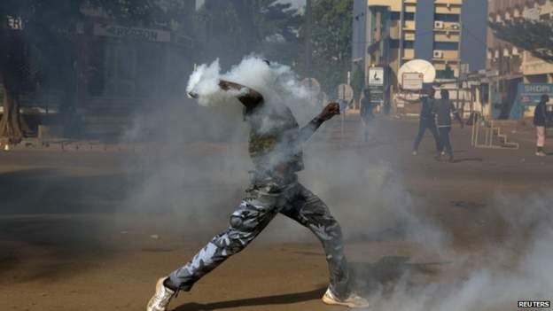 An anti-government protester throws a tear gas canister at riot police in Ouagadougou, capital of Burkina Faso, on 30 October 2014.