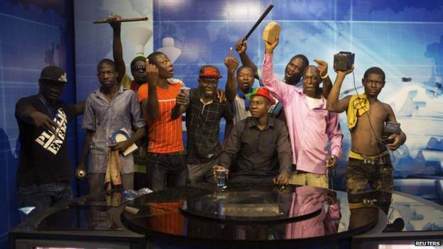 Anti-government protesters take over the state TV podium in Ouagadougou, capital of Burkina Faso, October 30, 2014.