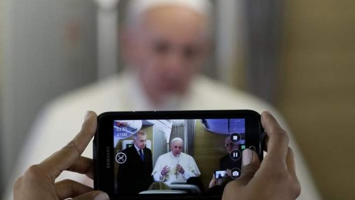 Pope Francis is framed in a smartphone as he greets journalists on board the flight to Nairobi, Kenya, Wednesday, Nov. 25, 2015. Pope Francis is travelling to Africa for a six-day visit that is taking him to Kenya, Uganda and the Central African Republic.