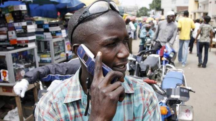 A motorcyclist phones sat on his motorbike holding a mobile phone on 18 August 2008 in Obalende, a district of Lagos, Nigeria.