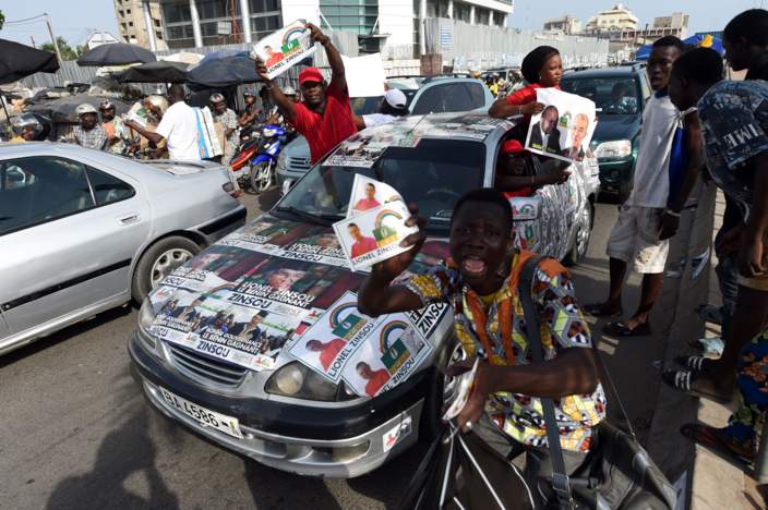 Supporters present posters of current Prime Minister Lionel Zinsou, a French-Beninese investment banker and candidate of the ruling party Cowrie Forces for an Emerging Benin (FCBE) during a rally in Cotonou, on March 3, 2016.