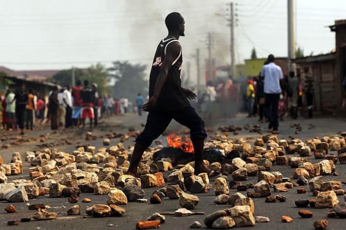 A man walks through paving stones and a tire fire during protests against the governing party on June 26, 2015 in Bujumbura, Burundi
