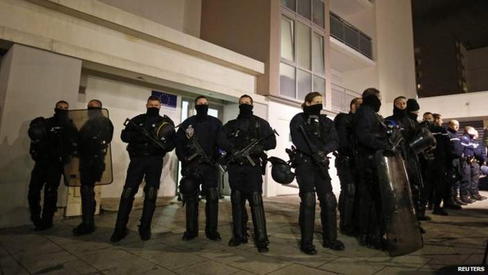 Police officers stand guard outside a flat in Reims as investigators search inside.