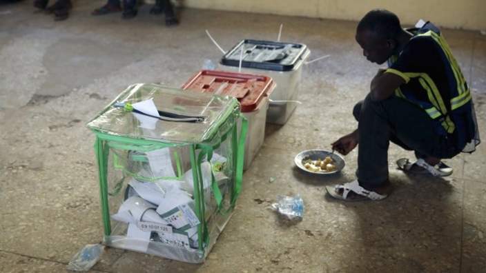 An elector worker eats his launch next to ballot boxes in a poling station in Kano - 28 March 2015