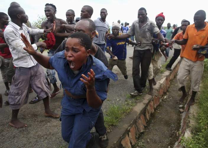 Protesters attack a female police officer accused of shooting a protestor in the Buterere neighbourhood of Bujumbura, Burundi, May 12, 2015