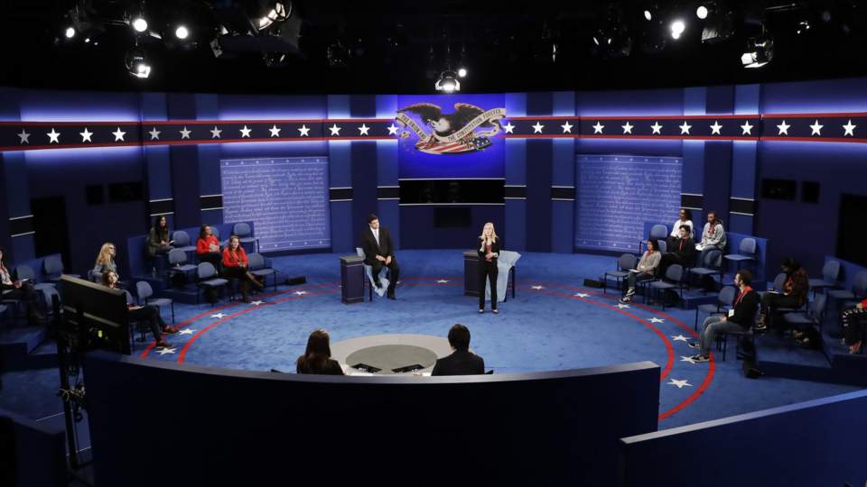 Students stand in on the stage as preparations are made for the second presidential debate