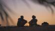 Silhouette of two nomadic people sitting around a camp fire at sunrise