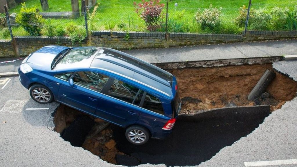 Car falls down huge hole in street