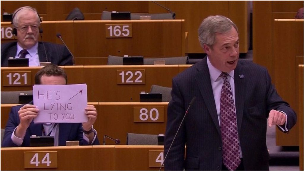 'He's lying' sign held behind Nigel Farage