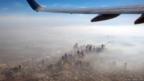 An aerial view of a city shrouded in smoke, as seen from a plane