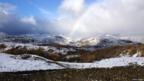 Rainbow on snow covered hills