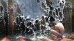 A boy plays in a local fountain to cool off