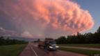 A truck drives as a supercell storm system looms in the sky overhead