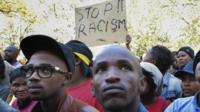 Protesters in South Africa hold up a "stop racism" sign