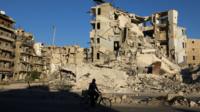 Man cycles past war-damaged buildings in rebel-held Tariq al-Bab district of Aleppo (26 September 2016)