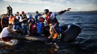 A man jumps off a rubber dinghy (boat) as he arrives with other refugees and migrants on the Greek island of Lesbos after crossing the Aegean sea from Turkey on October 12, 2015.