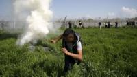 A migrant flees tear gas thrown by Macedonian police on the Greek border at Idomeni, 10 April