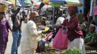 A street market in Libreville. A woman buys fruit from a femail fruitseller.