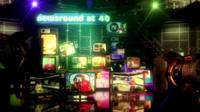 A stack of television screens show Newsround presenters from the 40 year history of Newsround.
