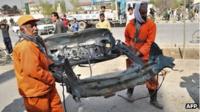 Two men carry a charred car part