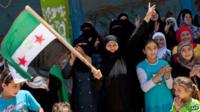 A Syrian woman holds a pre-Baath national flag, which was adopted by the opposition, during an anti-government demonstration after the Friday prayers in the city of Binnish in Idlib province on June 29, 2012.