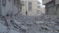 A rebel fighter walks near a building damaged after an air strike on Maarat al-Numan, 31 October 2012