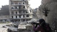 a Free Syrian Army fighter is in position in front of destroyed buildings in Aleppo, Syria on 29 November